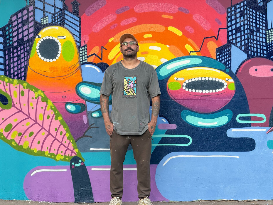 Celo Pax junto ao mural de sua autoria (Foto: Leonardo Schavetock/Divulgação)