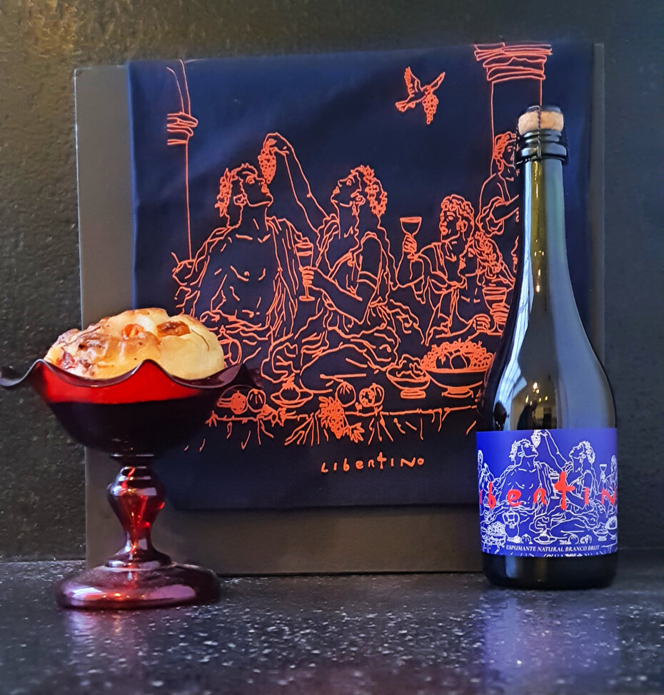 A casa acrescentou &agrave; sua carta de vinhos um espumante pr&oacute;prio com r&oacute;tulo da artista Daniele Stuani, que tamb&eacute;m assina a sacola ao fundo, ainda uma outra especialidade, o p&atilde;o salgado (Foto: Divulga&ccedil;&atilde;o) 